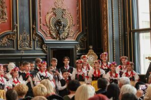 Śpiewające dzieci w trojach ludowych śląskich w sali pałacowej